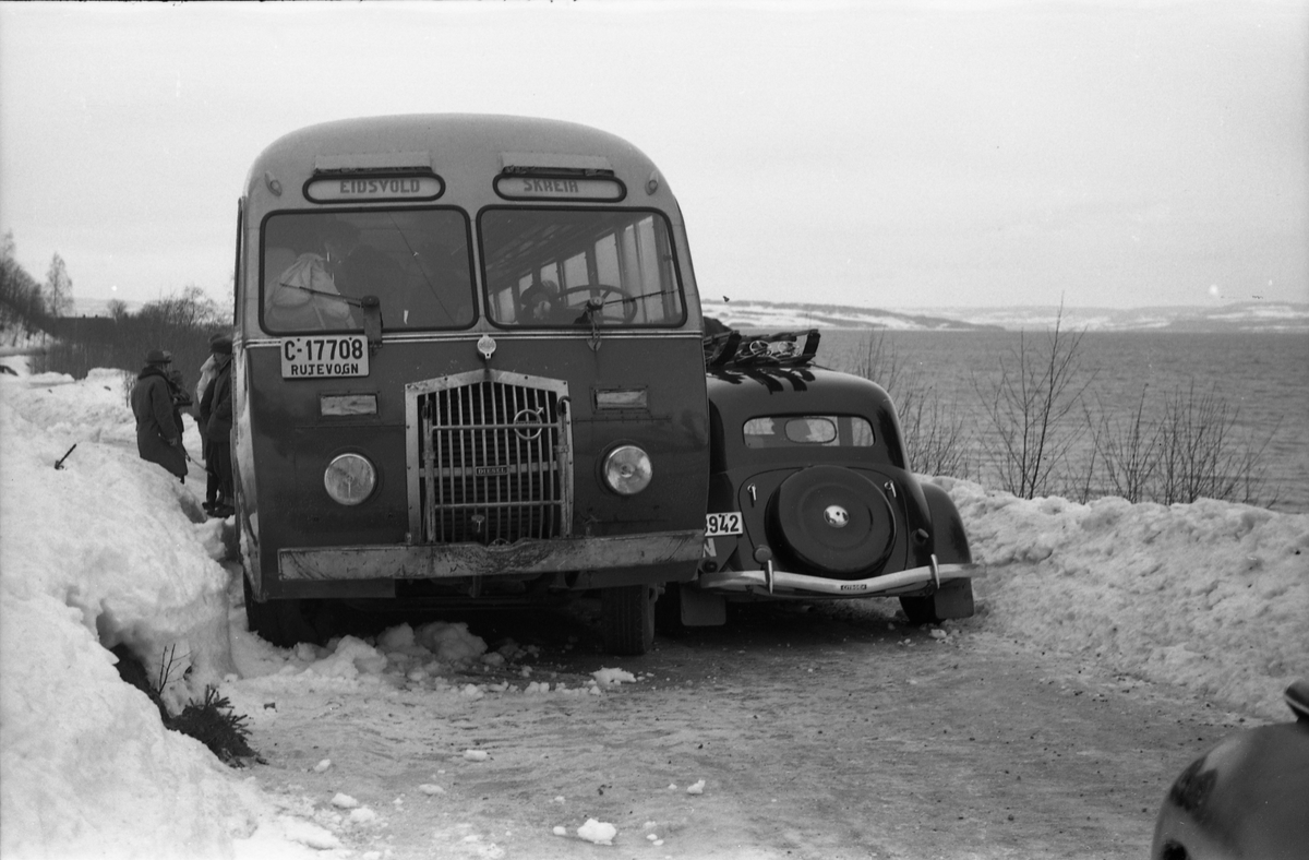 Møteuhell mellom buss og personbil på en trang Rv. 33 ytterst i Totenvika en vinterdag 1950. Bussen er "Eidsvollruta", bussen som gikk mellom Skreia og Eidsvoll. Serie på ni bilder.