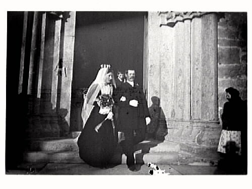 Bröllopsbild. Brudparet går ur kyrkan med en pojke bakom och en flicka står varmt klädd vid sidan.