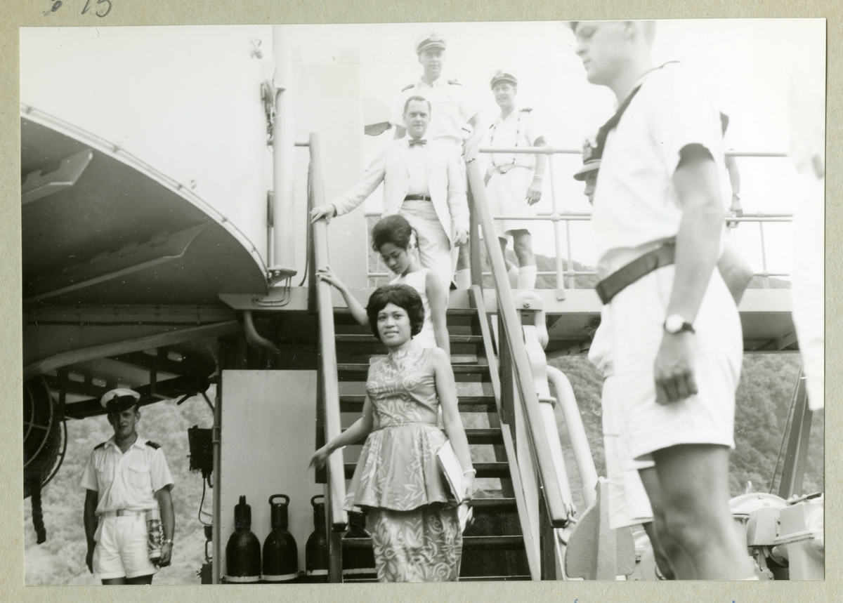 Bilden visar två fin klädda damer som går ner en trappa på örlogsfartyget Älvsnabben. De svenska sjömän i sceneriet står i giv akt. Enligt uppgifter från ett besättningsmedlem är det en prinsessan från Tonga som besökte det svenska minfartyget under sin långresa 19966/67.