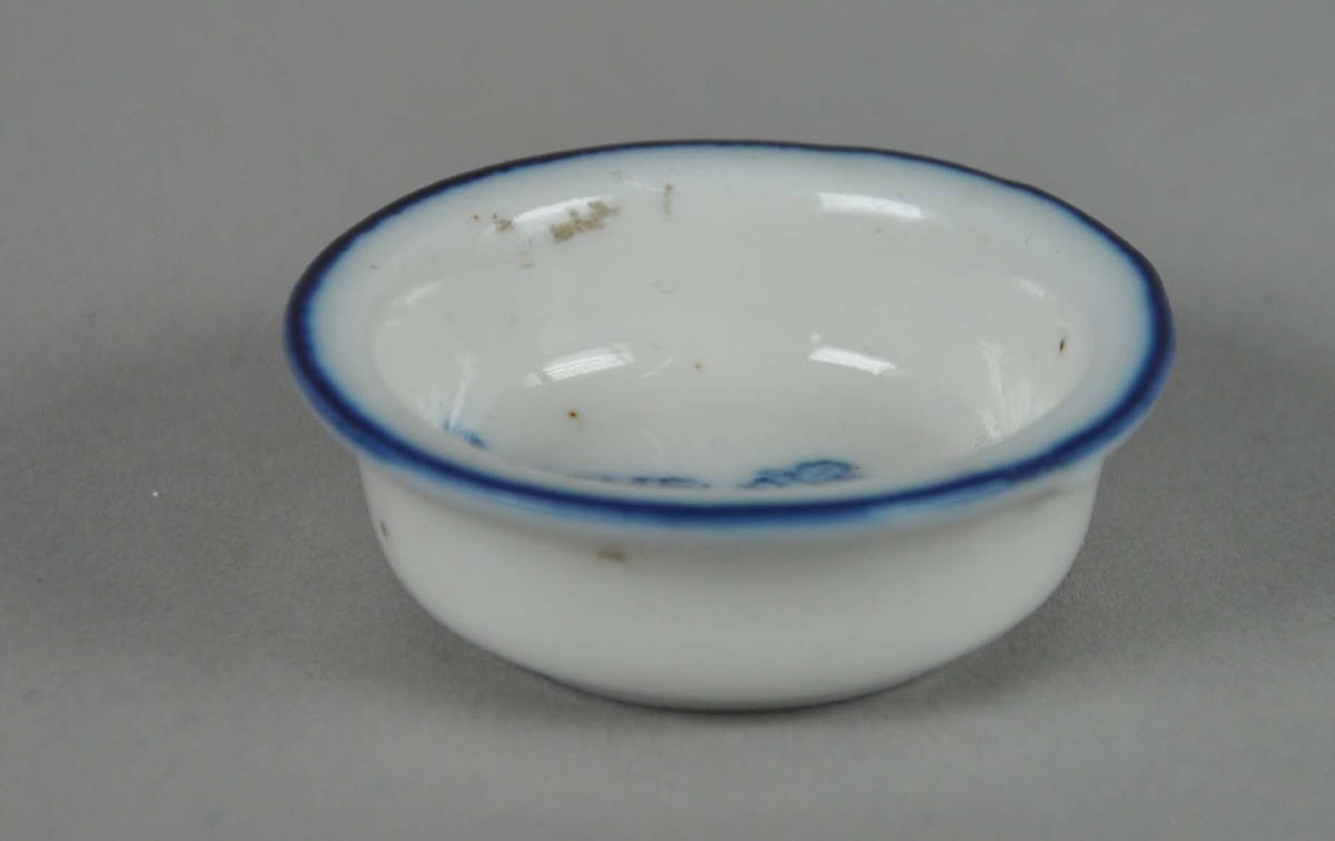 Lite kar av glassert keramikk, med blå innskrift og en blå stripe langs randen av karet.
