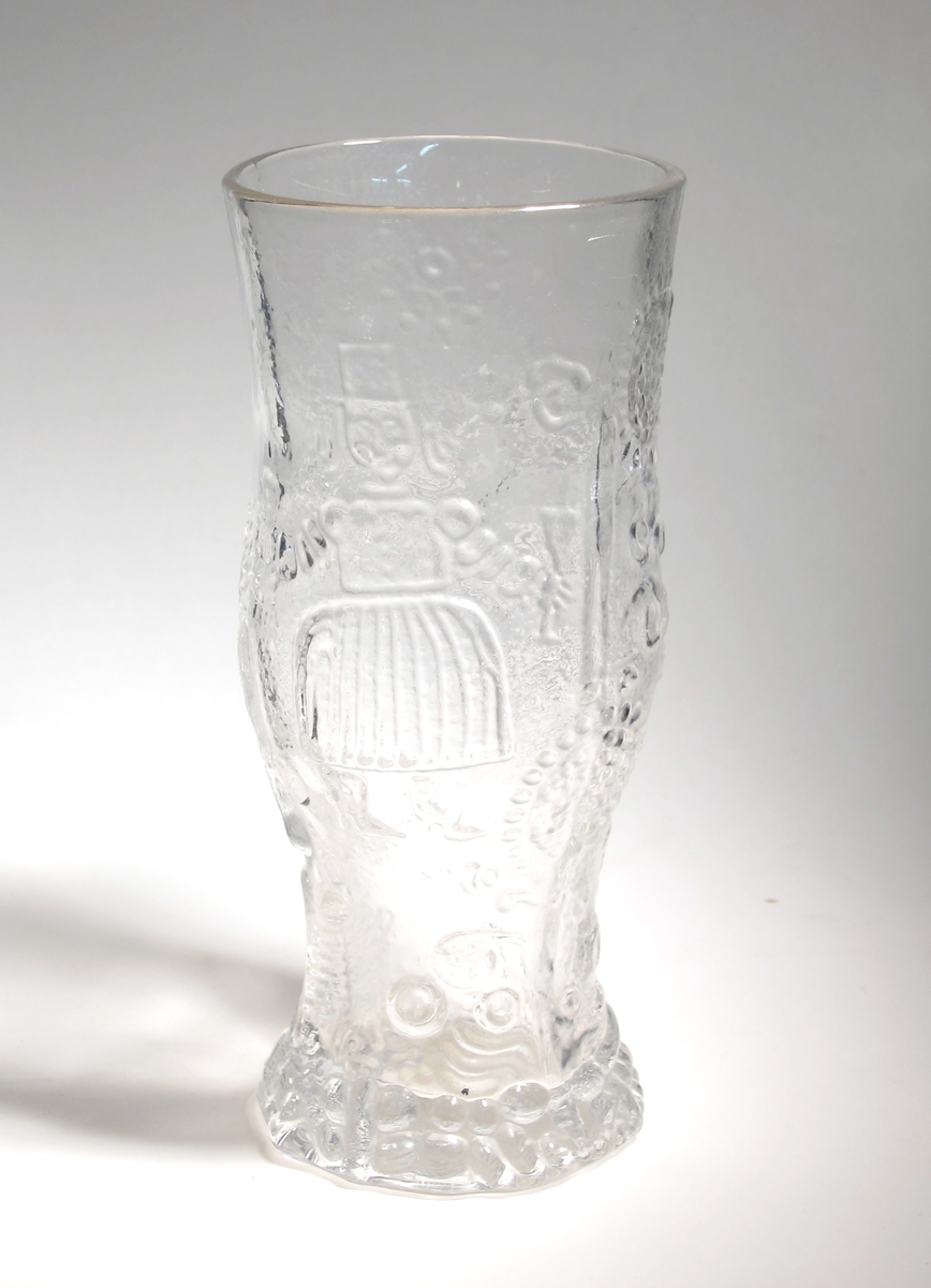 Ölglas.
Kupan är relativt hög och hela ytan är täckt av en relief med dalamotiv av allmogekarraktär.