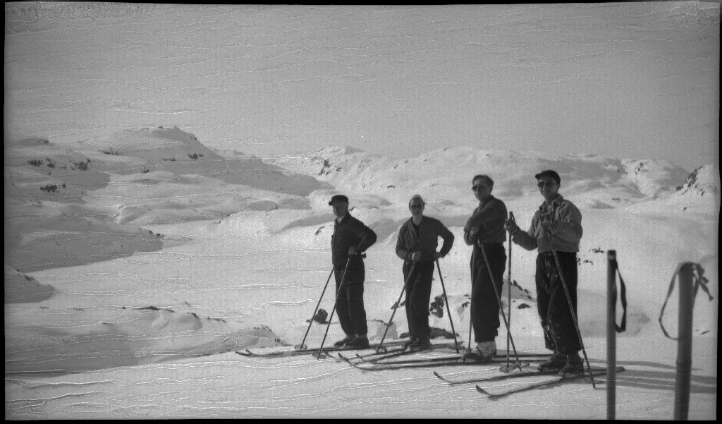 Fire unge menn på skitur fra Roalkvam til Stranddalen i Suldal. Det er bilder av hytter i fjellet, fra landskapet, lek med en hoppbakke og fra skigåing.