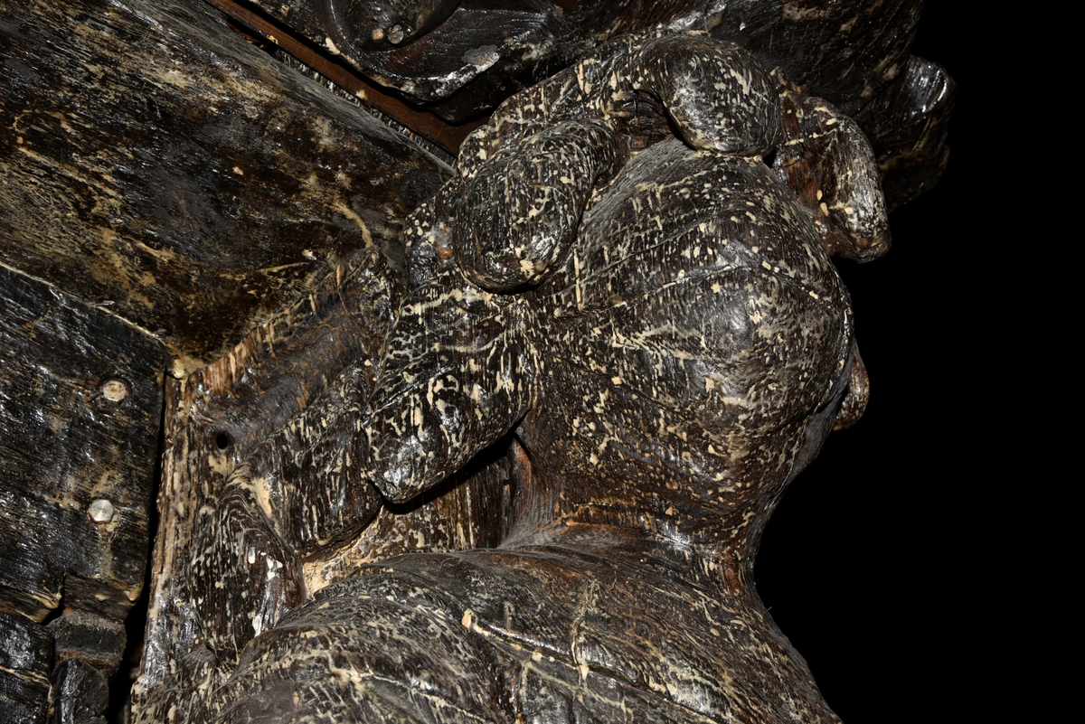 Skulptur av riddare i 1600-talsrustning med slutet visir.

Riddarens fältbindel är draperad från höger axel snett över bröstet och hjälmens plymer sträcker sig även ned utmed ryggen. Huvudet är kraftigt vridet mot höger och höger arm hålls framsträckt. Vänster arm förefaller ha varit sträckt utmed sidan. Vänster underben är delvis fragmentariskt men har tydligen varit placerat bakom höger ben som är lätt böjt.



Skulpturen är snidad i ett stycke så när som på armar, höftparti och fötternas ytterändar som är utförda separat och fastsatta med dymlingar och spikar. Troligtvis har skulpturen varit utrustad med svärd eller lans, kanske också sköld.



Skulpturen har ett mycket kraftigt bakstycke. Sett från sidan är bakstycket närmast kilformigt och dess baksida är upptill försedd med en klossliknande, snedställd "puckel" som i det närmaste täcker hela övre delen av bakstyckets baksida. I övrigt är denna slät. Bakstycket är snidat separat och skarven går utmed figurens rygg. Hjälmens plymer fortsätter ut över bakstyckets sidor. Genom bakstyckets kraftiga bredd upptill blir det parti som täcker figurens hjässa ovanligt långt. Figuren är i det närmaste diagonalställd i förhållande till bakstyckets bakre kant vilket ger den en framåtlutande hållning.



Text in English: Sculpture of a knight in seventeenth-century armour with closed visor.

His field badge is draped from his right shoulder across and over his chest. His elegant plumes fall down his back. The head is twisted sharply to the right and the right arm is held out in front. The left arm appears to fall beside his left leg beneath the field badge. The lower left leg is rather fragmentary but was obviously placed partially behind the right leg, which is slightly bent.



The sculpture has a very robust reverse side which, when seen in profile, is almost wedge-shaped. The upper reverse side has a block-like, angled "hump" which virtually covers the upper part of the back-planking's reverse side. Otherwise it is smooth. The whole of the back-planking has been carved separately from the actual figure, the seam runs along the back-planking's sides. Because the back-planking is so wide at the top there is a section that goes quite a long way out over the figure's head. The figure is positioned almost diagonally in relation to the reverse side of the back-planking, which gives the figure a forward-leaning posture.