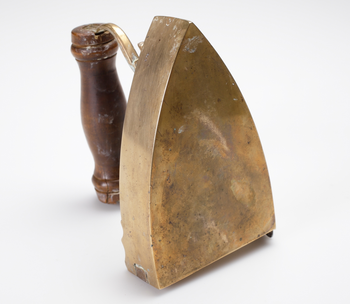 Lodstrykjärn av mässing. 
Försett med handtag av svarvat trä, lucka för kol. Graverat motiv på ovansidan av strykjärnet i form av blomdekor och årtal:"1832".