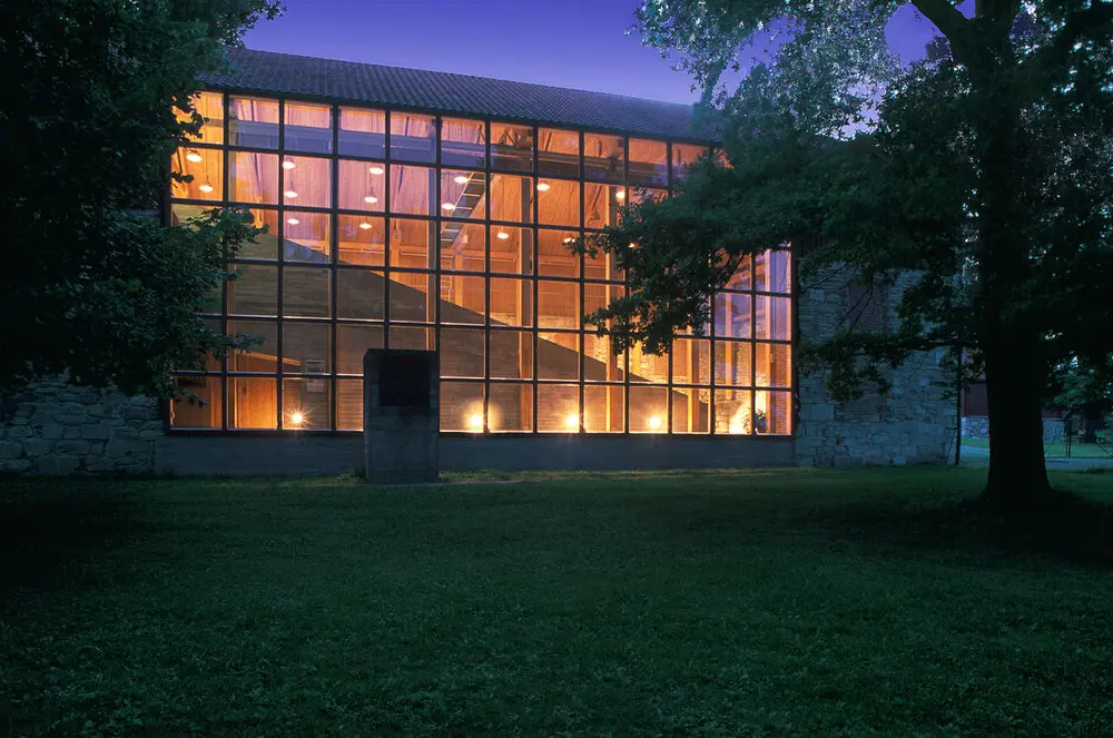 Sørveggen på Storhamarlåven hadde falt ut da Sverre Fehn skulle bygge om låven til museum. Han responderte med å sette opp en vindusvegg i det store hullet.