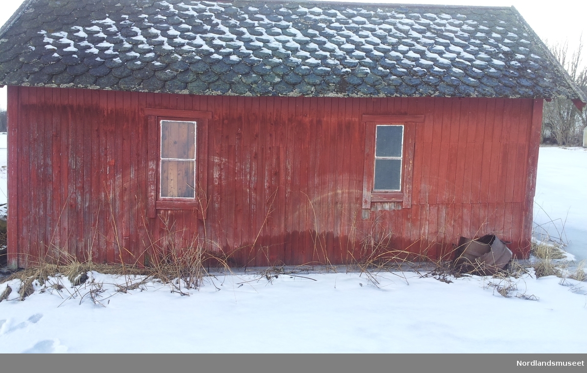 Bygget er et uthus med rødmalt panel og skifertak