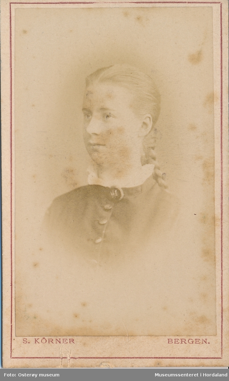 portrettfotografi av ung kvinne med mørk jakke, kvit krage og hårflette i nakken