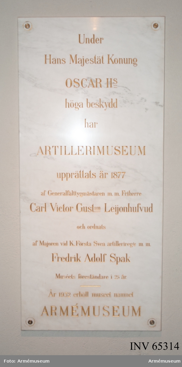 Grupp M V.

Minnestavla föreställande Armémuseums stiftare och förste föreståndare. Rektangulär marmortavla, fastsatt med en förgylld metallrosett i varje hörn. Inskription i inhuggna, förgyllda bokstäver: "Under Hans Majestät Konung OSCAR IIs höga beskydd har ARTILLERIMUSEUM upprättats år 1877 af Generalfälttygmästaren mm. Friherre Carl Victor Gustson Leijonhufvud och ordnats af Majoren vid K Första Svea artilleriregte mm. Fredrik Adolf Spak Muséets föreståndare i 25 år, på 13 rader". Material: Carraramarmor.