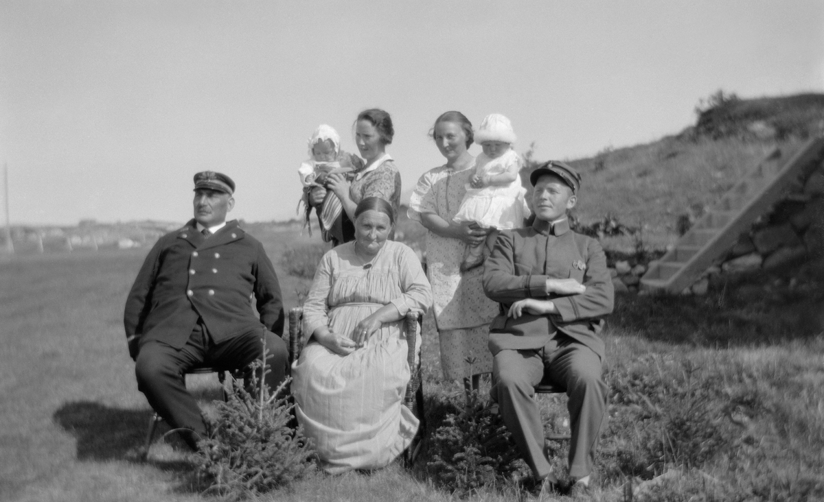 To menn, tre kvinner og to små barn fotografert utendørs.