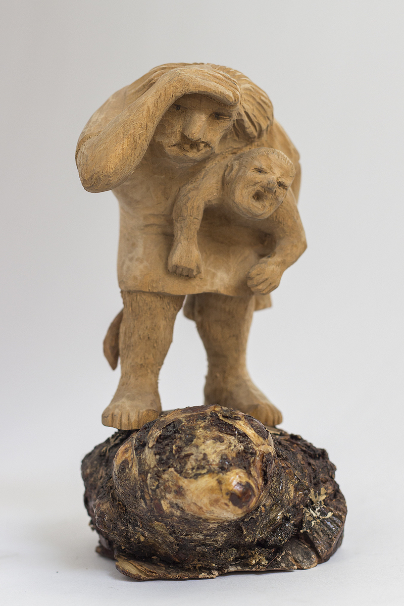 Treskulptur, på plint av kåte, av troll med trollunge under armen.
