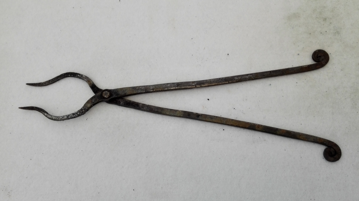 1 loddetang  En tang med 31,5 cm lange arme, i enden utsmidd til to tynde spidser, anvendt til ved lodning av mindre gjenstander at holde disse sammen. Kjøpt av gaardbruker Bjørn K. Gjeithus, Arnefjord.