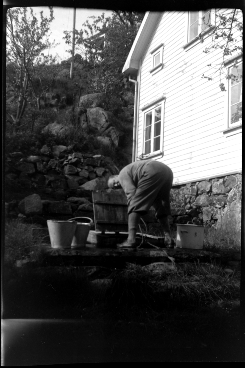 Bjarne Trygvesson Sundt henter vann foran huset til Agnes Sundt, Loshavn. Fotografert ca. 1953.