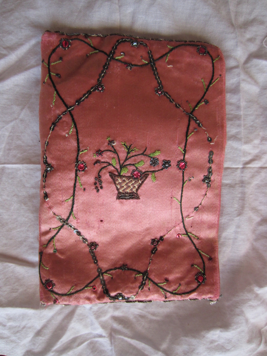 Veske til å oppbevare lommetørkler (også omtalt som mappe). Rosa silke brodert med farget tråd, perler og paljetter. a) veske, b) lommetørkle med rosa broderte blomster, c) lommetørkle med hvite broderte blomster.