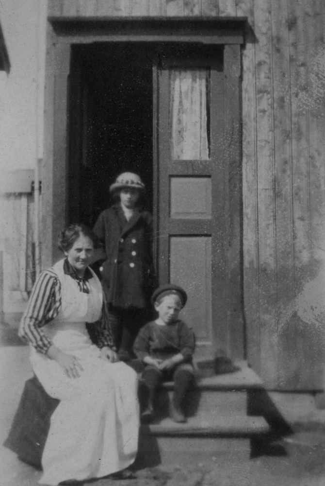 Fru Andersen på Tippen på trappa i Strandgata med to barn.