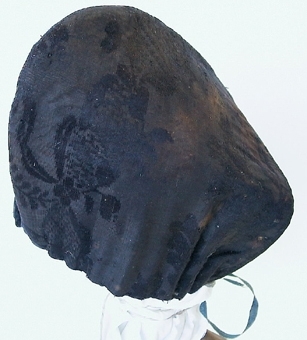 "Kammamössa" av siden med grovt linnefoder, sydd av två delar med en söm över nacken. Ett blått linneband är draget genom en sydd kanal nertill.