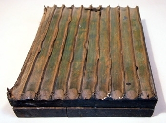 Tryckstock av trä med infällda metallskenor som vid tryckning bildar ränder.