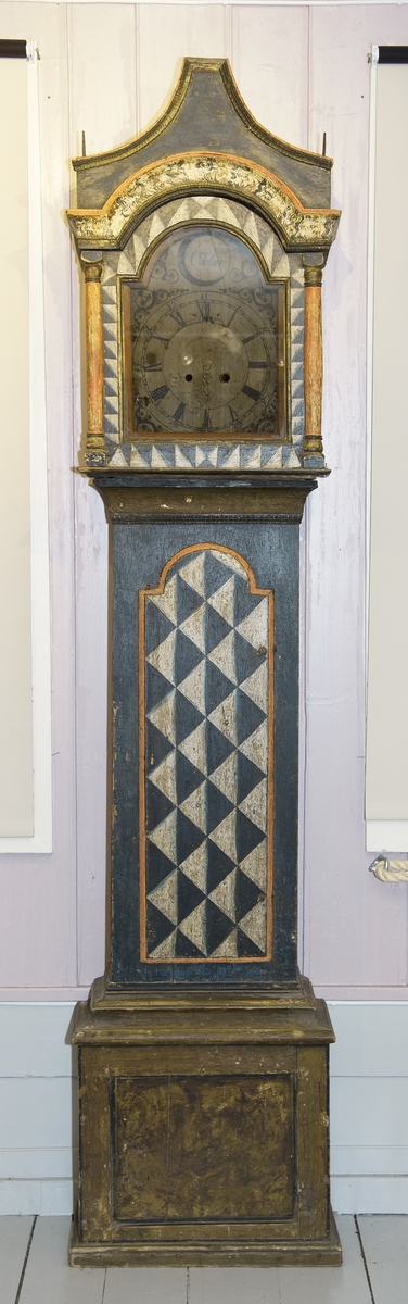 Malt gulvur fra Fjell Nordre i Nord-Odal. 
Den opprinnelige dekormalingen er avdekket på store deler av klokka. Nederst på klokkekassa er den overmalt med brun maling.