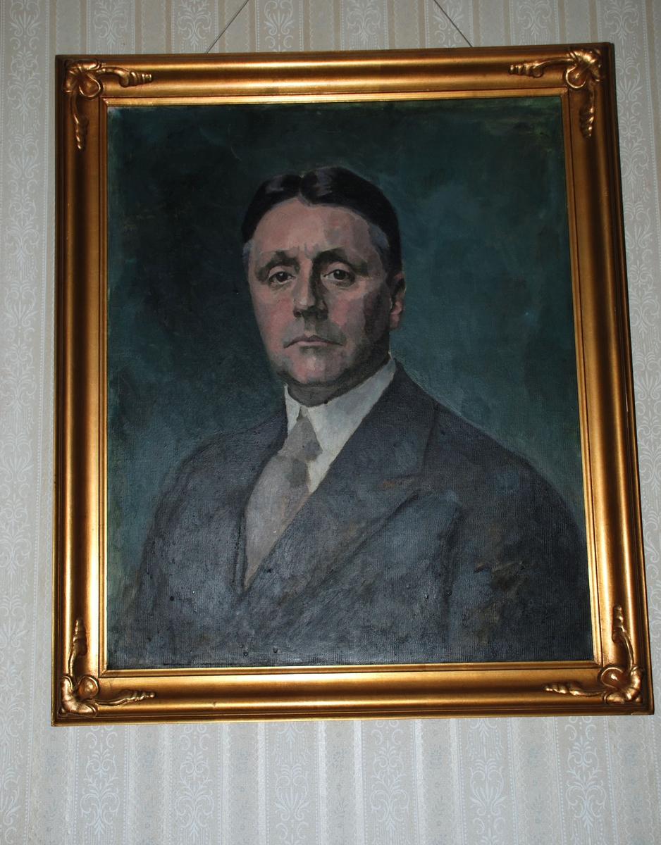 Gullramme med blader i hjørnene.
Forestiller Hans B. Fasmer, født 1875.
Iført stålgrå dress, hvit snipp, lysegrått slips.
Dreiet mot høyre. Grågrønn bakgrunn.