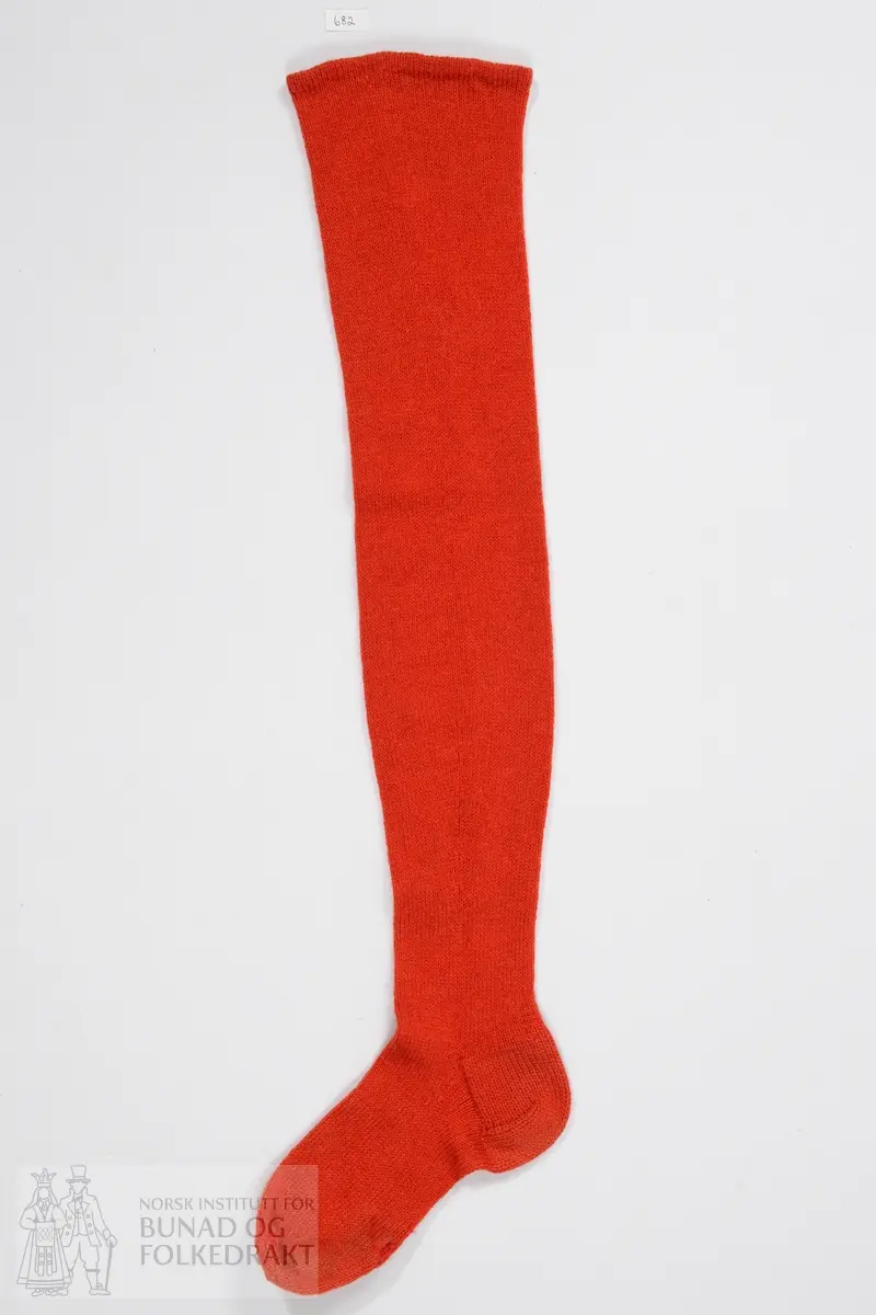 Sokk. Strikket i rød ull. Lang strømpe i glattstrikk. Strømpen er lik den i registrering nummer 0681, men denne har en annen type hæl.