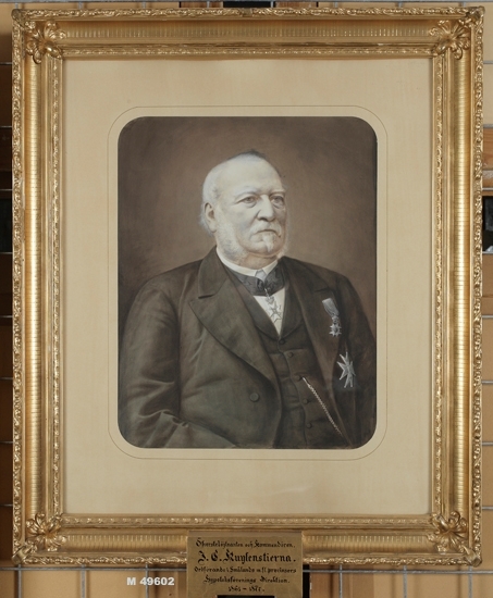 Litograferat (delvis handkolorerat) porträttfoto av överstelöjtnanten m.m. 
Johan Carl Kuylenstierna (1813-1880). 
Man iklädd bonjour med väst och ordnar m.m. på bröstet.
Midjebild, halvprofil.