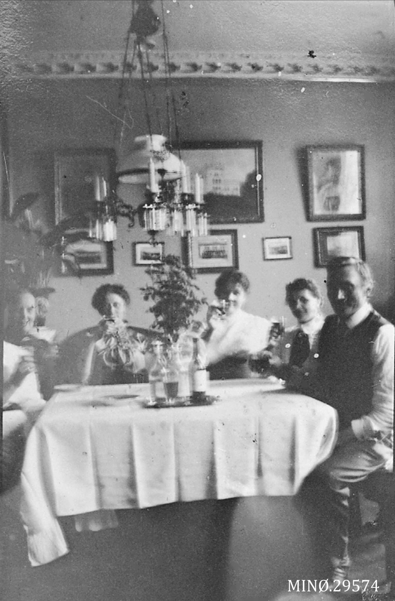 Personer rundt et stort bord. Bak på bildet sto det:
"Hjemme hos os da stor-Ola var her i 1914. Ole ved bordet. Min hustru er synlig bare halvøten. Jeg var fotograf"