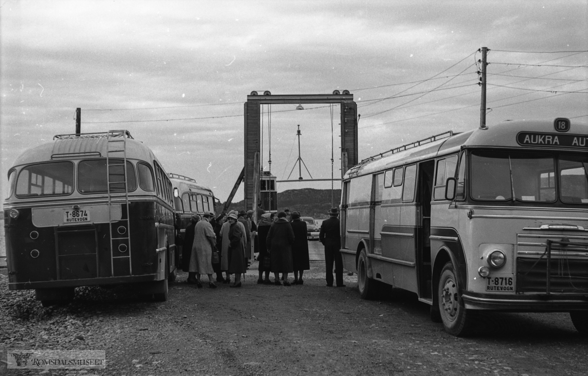 "Årsmøte husflidslaget"."Raknes 1959".T-8716 var en kombinertbuss, Commer med karosseri fra T. Knudsen i Kristiansand, 1956-modell. Den tilhørte Aukra Auto og gikk i rute Aukra-Molde og Aukra-Ålesund over Otrøy..T-8674 var en personbuss, Commer 1959-modell, som tilhørte Otrøy Auto. Det var en Commer med karosseri påbygd hos Brødrene Solheimdal, Solemdal i Molde. Men alt i 1960 ble bussen solgt til Ålesund i bytte med en ny buss. Den fremste bussen på venstre side synes også å være en buss fra Otrøy Auto.