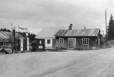 Dette er Amund Sandbergs smie og sykkelverksted på Sand mot slutten av 1930-tallet. Her ble det også bygget busskarosserier. Sandberg var forhandler for «Tiger» bensin. Ukjent fotograf.