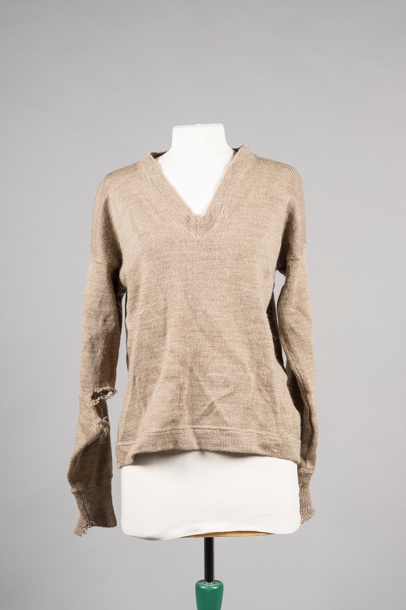 Beige strikket og sydd genser, ribbestrikket ved mansjettene.