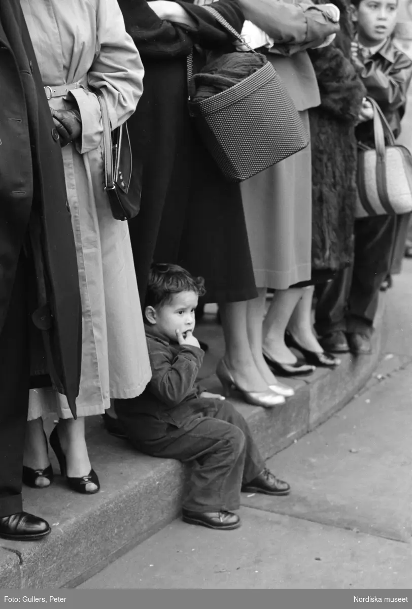 London. Publik vid ett evenemang. En pojke sitter på trottoarkanten.