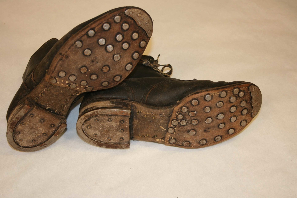 Halvhøge lerstøvlar med jernbeslag under hæl og sole.