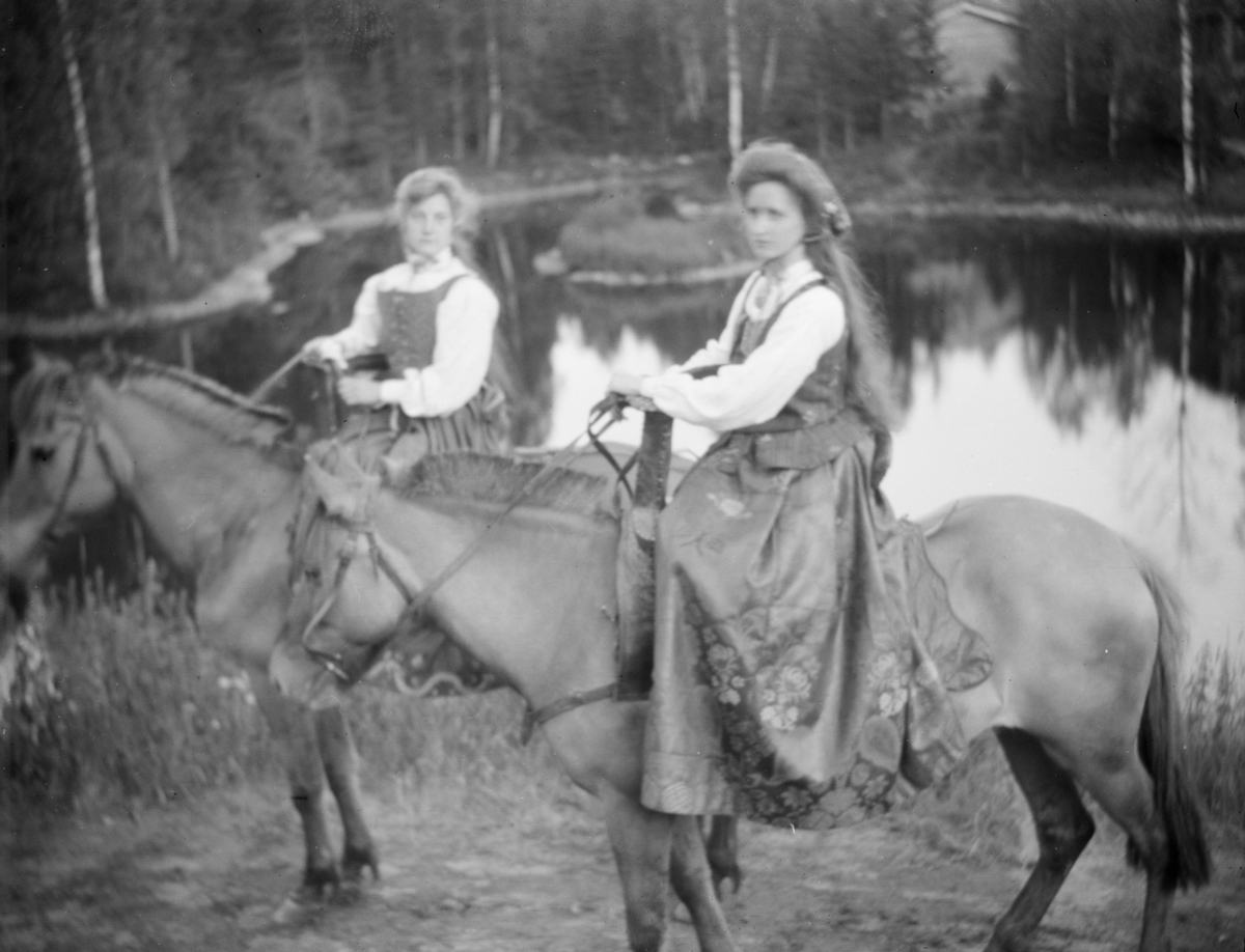 To kvinner i bunad til hest