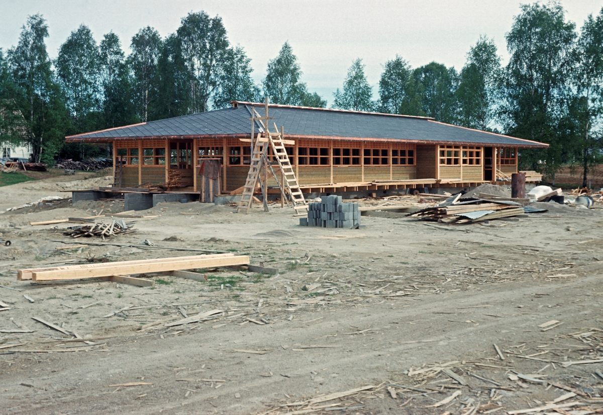 Bygging av nytt kontorbygg ved trelastbedriften Våler skurlag i Solør, muligens sommeren 1966.  Huset ble reist i en etasje, med et slakt utkraget valmtak, noe som fikk lokalbefolkningen til å omtale det som japanskinspirert.  Bygginga av dette kontorkomplekset var ett av flere tiltak som ble nødvendige i andre halvdel av 1960-åra, da Våler skurlag gjennomgikk en kraftig ekspansjon.  I 1963 hadde virksomheten hatt et årsforbruk på snaut 18 000 kubikkmeter.  I 1970 hadde dette økt til over 100 000 kubikkmeter.  Med denne utviklinga fulgte det et behov for flere ansatte, særlig i produksjonen, men også i administrasjonen.  Huset ble bygd med kjeller, som ble flyt med sand fordi man mente at man ikke hadde behov for dette volumet, men seinere tømt og tatt i bruk.