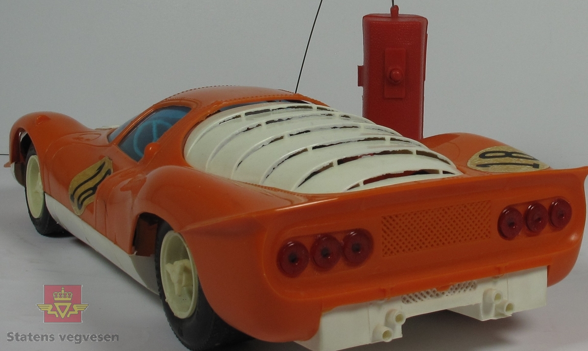 Miniatyr, lekebil i eske. Laget hovedsakelig av papp med plast og har primært fargen hvit. Bilen er helt oransje. Skala. 1:10