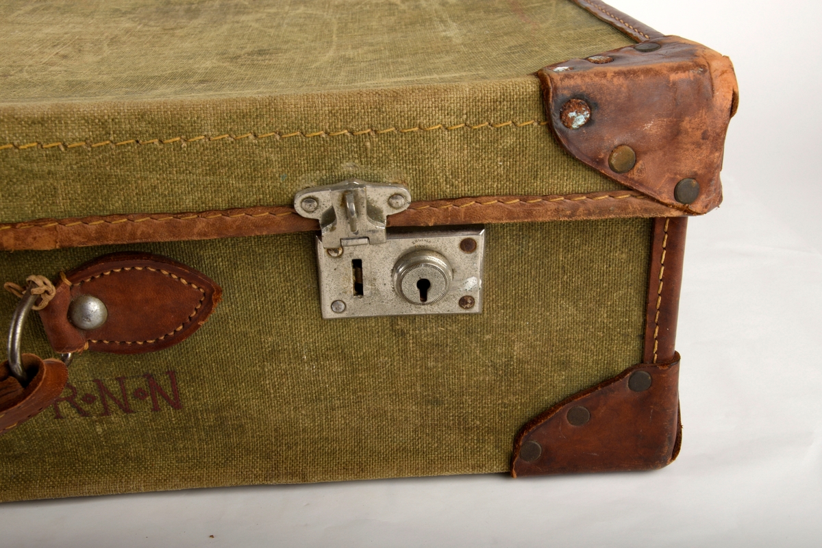 Rektangulær koffert av seilduk. Kofferten har to spenner til låsing på fremsiden og bærehank.