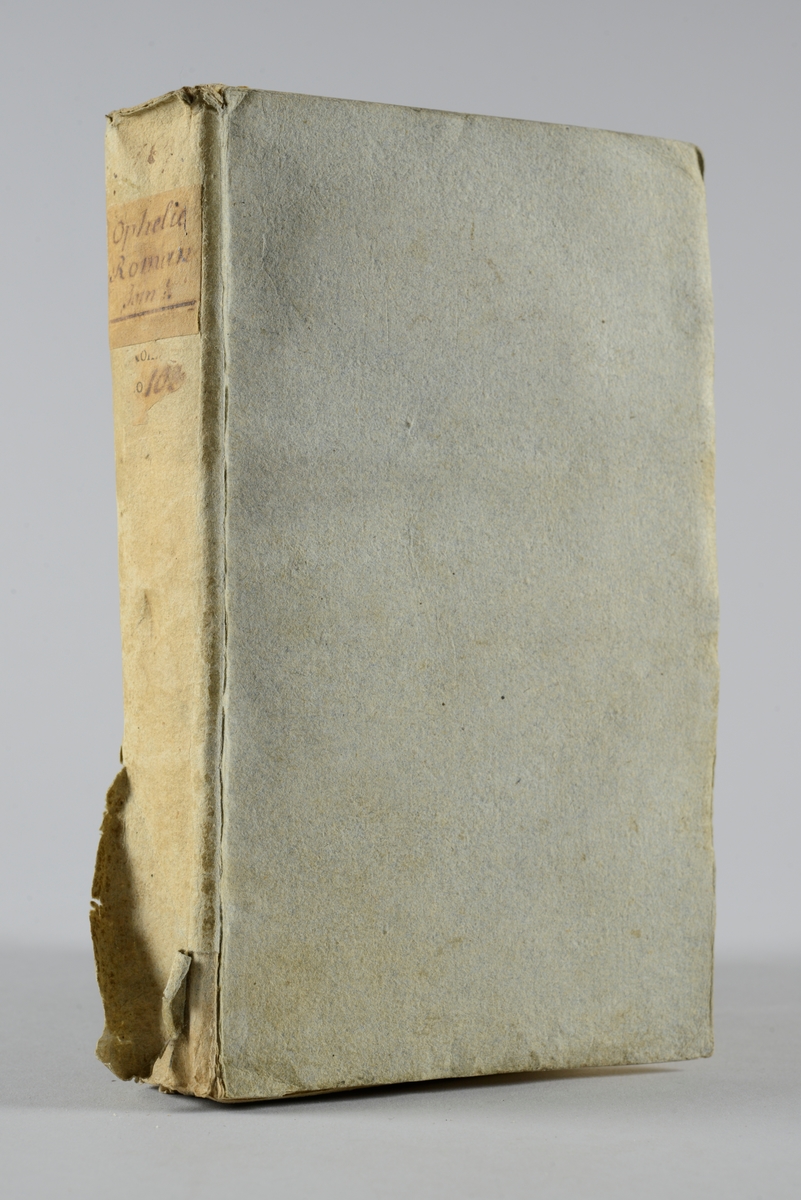 Bok, pappband,"Ophelie", del 1, tryckt 1763 i Amsterdam.
Pärm av grått papper, oskuret snitt. På ryggen pappersetikett med volymens namn och nummer.
Anteckning om inköp på pärmens insida.