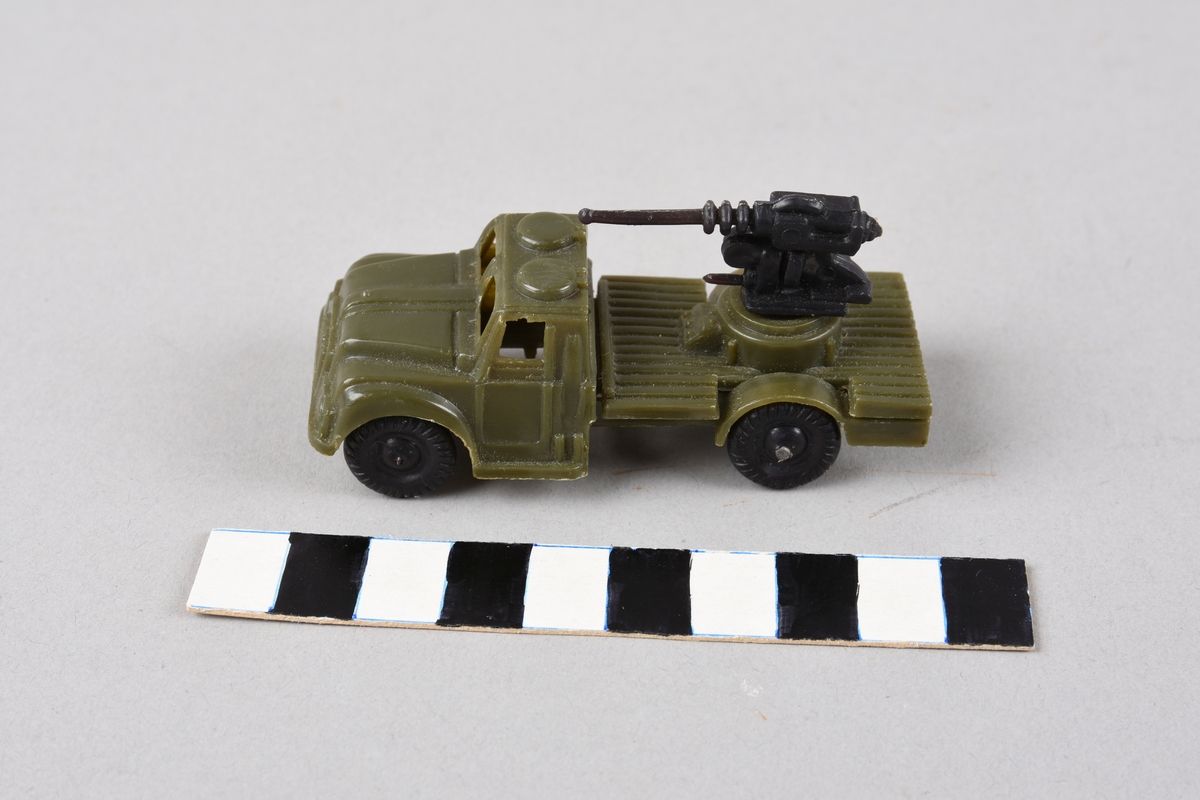 Militær leikelastebil med skyts på lasteplanet på en rund lavett som kan dreiast. Støypt i plast