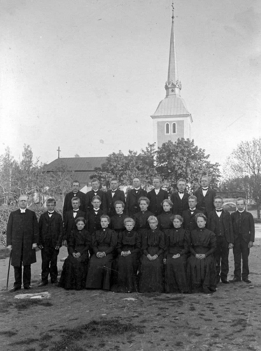 En konfirmationsgrupp samlade utanför Himmeta kyrka, sekelskiftet 1900.  Namn se bild 2. Gåva 1934 genom O. Blomquist. Fotograf: Walfrid Westman. Köping.;