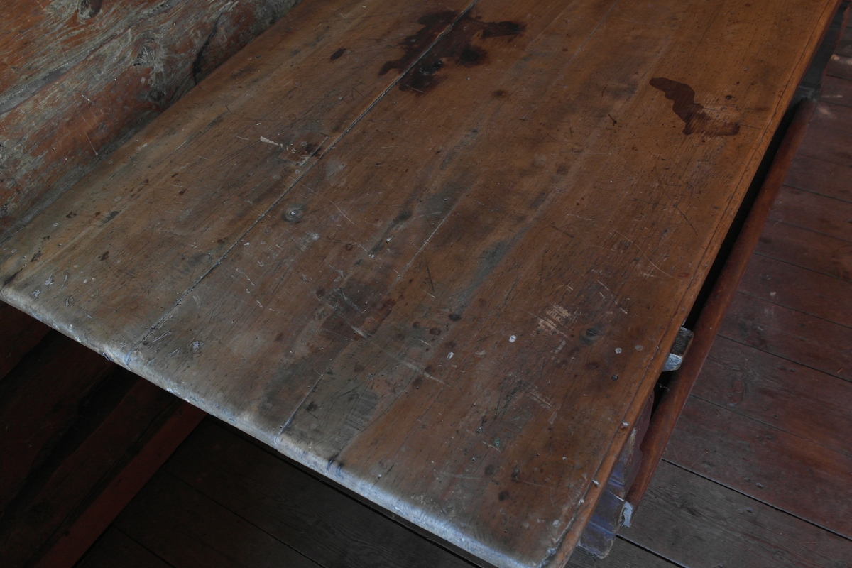 Langbord i høvlet, pusset og malt furu. Bordet er sammenføyd med hengsler. Bordplaten består av tre umalte bord. Sargen har skuffeåpning, men skuffen mangler. Understellet er brunmalt. Det har balusterformede bein forbundet med en langsgående fotlist.