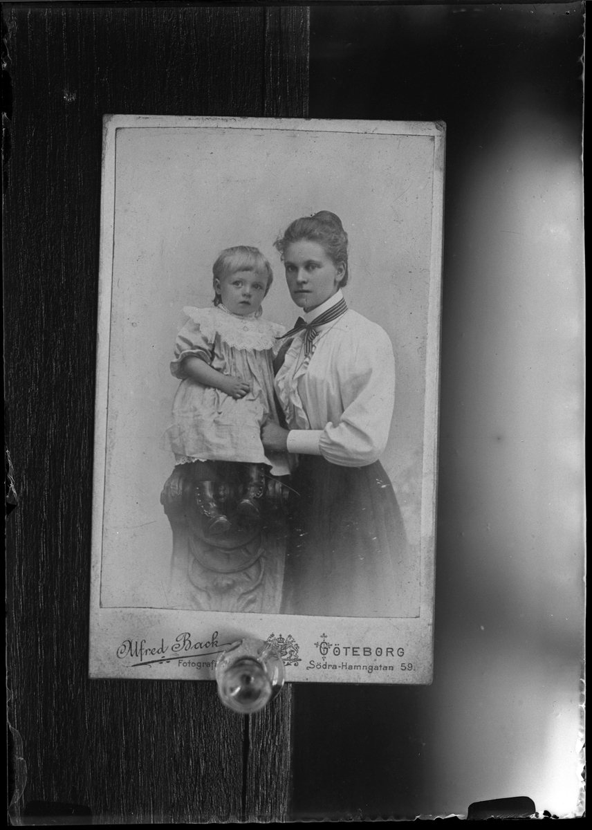 Reprofotografi av ateljéporträtt på en kvinna som håller ett barn. Ursprungsbilden är tagen hos Alfred Back på Södra Hamngatan 59, Göteborg. I reprofotografens anteckningar står det "Rep. för Ruth Färdig".