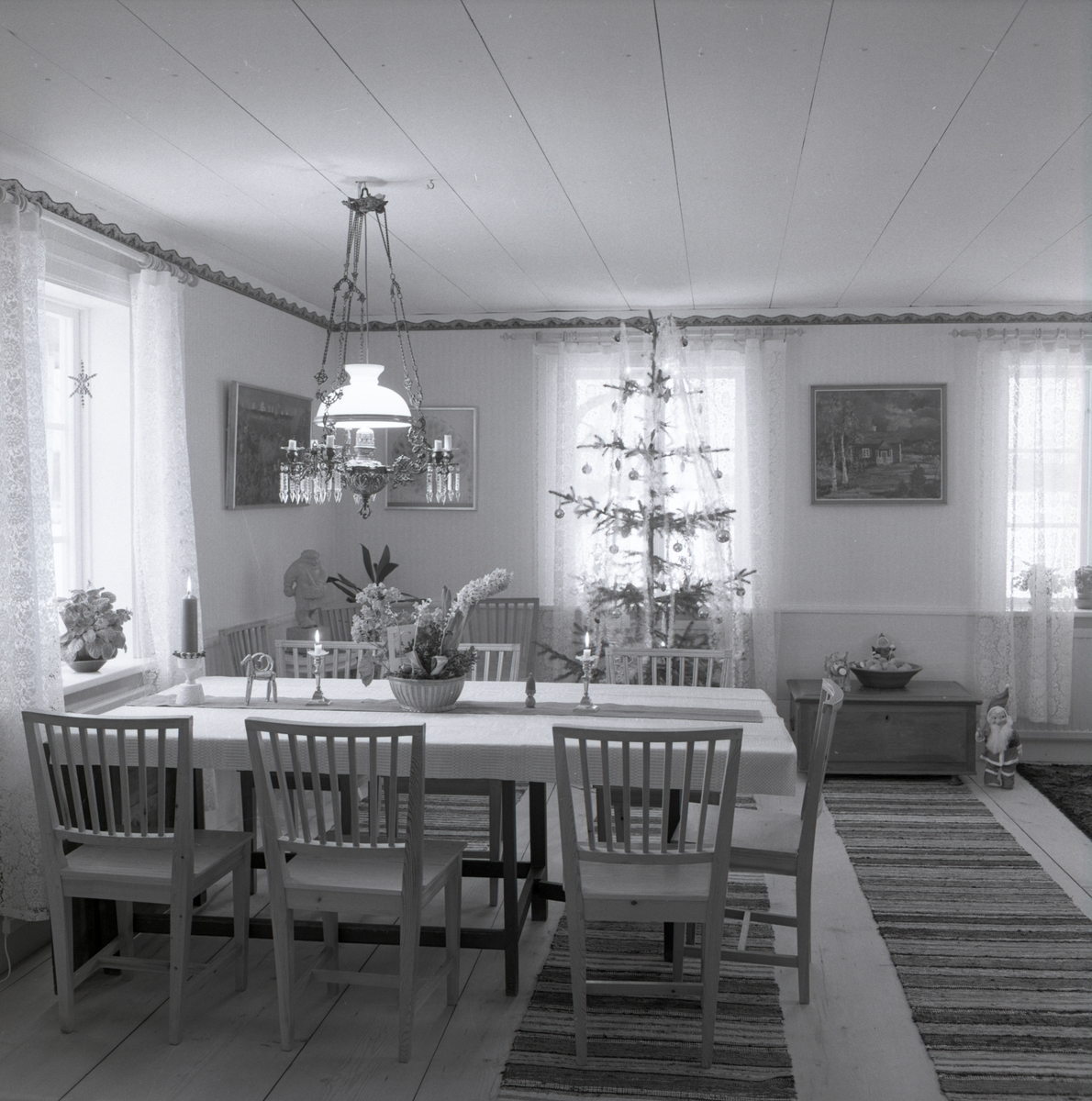 I ett rum på gården Sunnanåker finns en julgran, en taklampa, ett matbord med stolar samt en tomte, januari 1970.