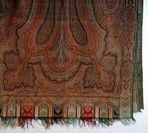 Ylleschal i persiskt mönster i många färger, rött dominerar. Fransad vid kortsidorna.Mindre hål och stoppar.