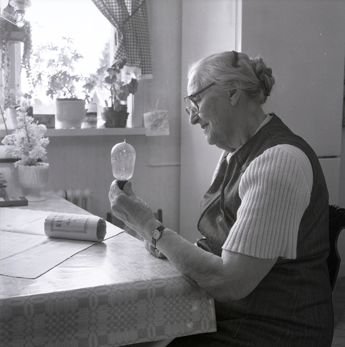En kvinna sitter vid köksbordet och tittar på en glödlampa i Sidskogen den 7 mars 1990.