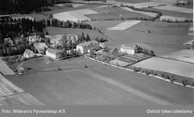 Haugetun ungdomsskole med bolighus til venstre og flere gårder i bakgrunnen. Tatt fra Rolvsøysund/ visterflo.