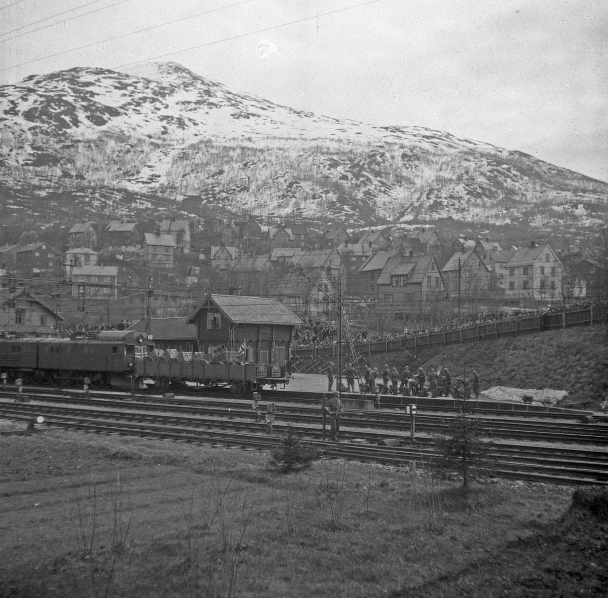 Norske politisoldater ankommer Narvik stasjon. Toget ble trukket av et elektrisk lokomotiv av type El.3. Foran loket var det plassert en åpen godsvogn bemannet med norske soldater og en kanon i tilfelle det var tyske soldater som ville forsøke å stoppe toget.
