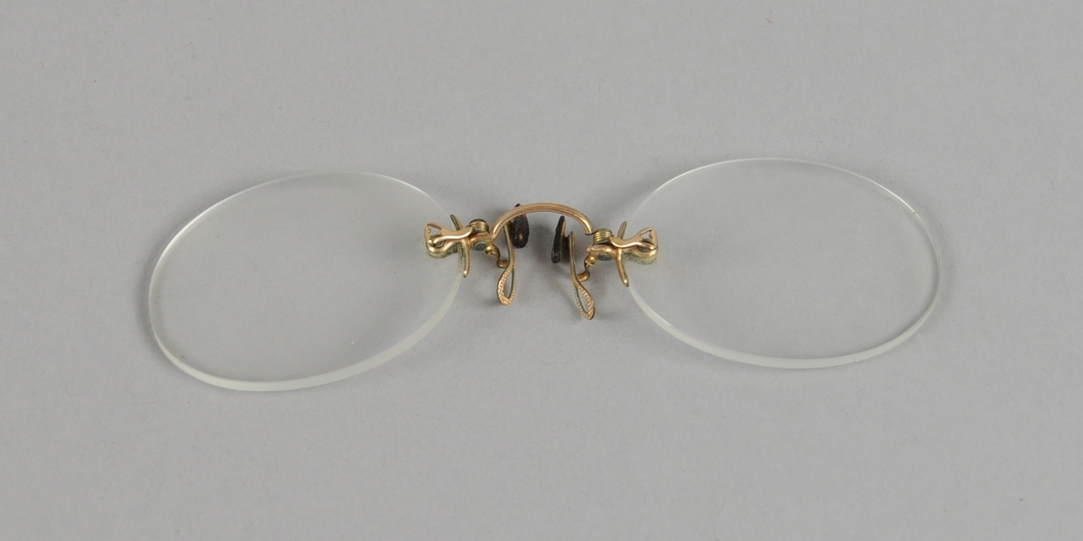 Lorgnett bestående av to brilleglass med nesebøyle av metall. Nesebøylen er brukket.
