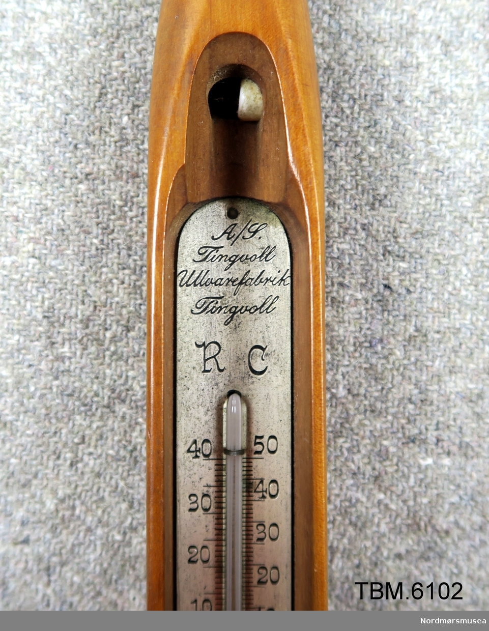 Fin polert vevskei med eit termometer i rommet der spolen skal vere.
Reklame for Tingvoll Ullvarefabrikk