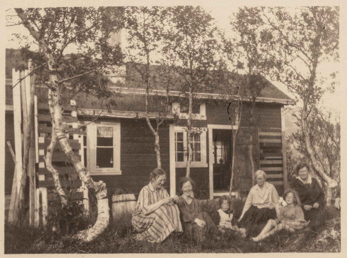 Kvinner og unger foran hytte i Tømmeråsen.