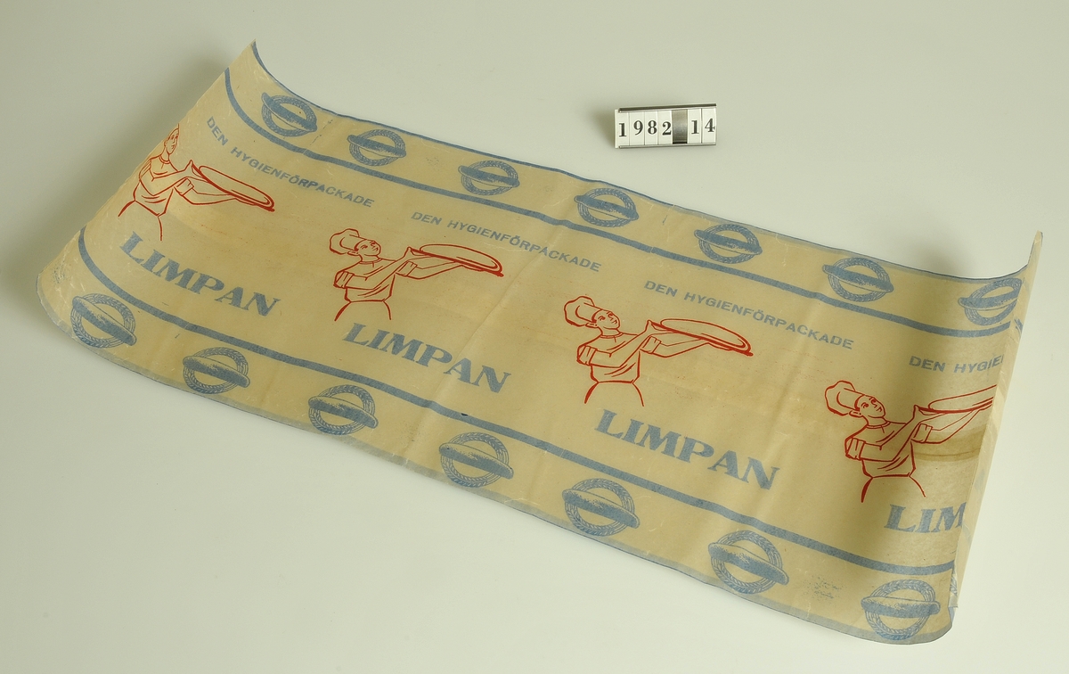 Av vaxat papper med rött och blått tryck
och texten: "Den hygienförpackade limpan"

Storlek: 22 x 51 cm.
Funktion: För bröd.