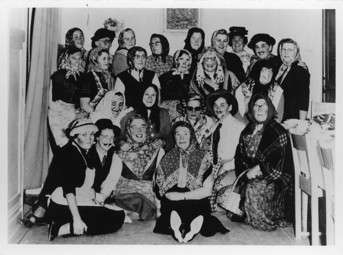 Gruppbild med 24 kvinnor, stående och sittande, från Alingsås Kooperativa Kvinnogille, klädda som påskgummor och påskgubbar under en påskfest.
