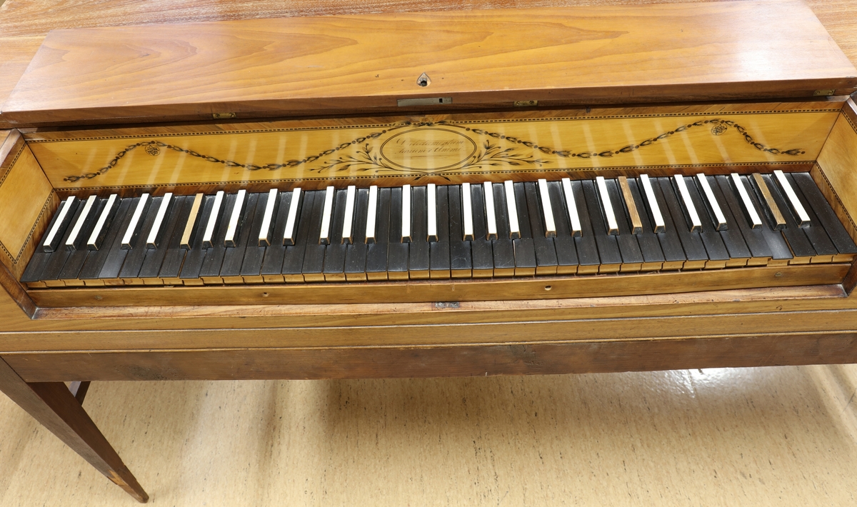 Hammarklaver i trä med svarta tangenter. Klaveret är delbart, med en bordsdel placerat löst på en ram med fyra kvadratiska avsmalnande ben.

Dekoren ovanför tangenterna är av ljusare trä inramat med en bård med intarsia i ljusare och mörkare trä. Enligt Benjamin Vogels inventering "Kulturhistoriska museets pianosamling, STM 1994-95", är detta typiskt engelskt. I mitten på namnbrädet finns inskriptionen "Delectamentum Aurium & Animi" Runt om  inskriptionen finns dekor av växtslingor i intarsia.

I instrumentets insida finns en springa i resonansbotten som lär vara speciell för dessa instrument, enligt Benjamin Vogel, som gör att dateringen kan vara runt sekelskiftet 17-1800.